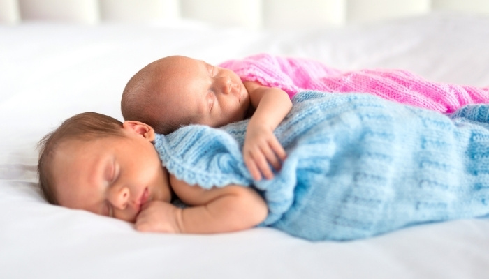 Boy and girl infant twins sleeping closely together.