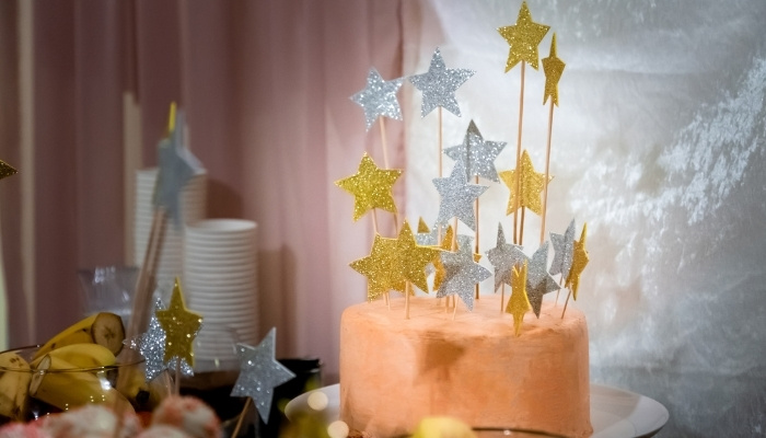 A peach-colored cake decorated with tall silver and gold stars.