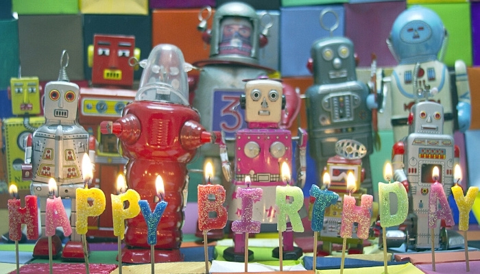Happy Birthday candles in front of robot toys.