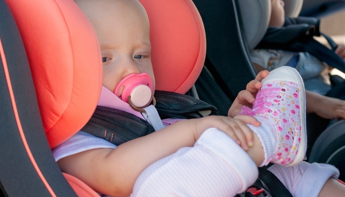 Two twin babies loaded in car seats for a road trip.