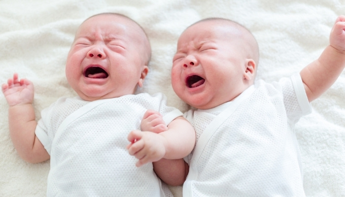A set of very angry twin babies dressed in white.