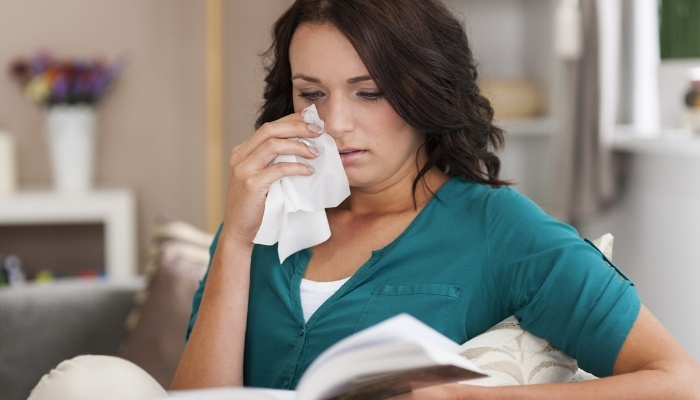 A woman crying while reading a book.