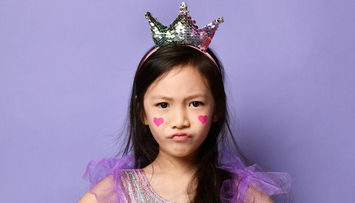 Young girl dressed as a princess with an angry expression on her face.