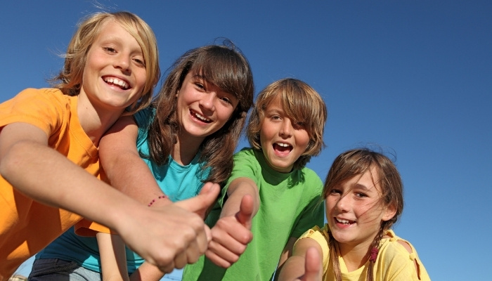 A group of four preteens all giving the thumbs up sign.