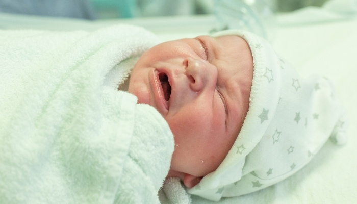 A newborn baby in a hospital bassinet.