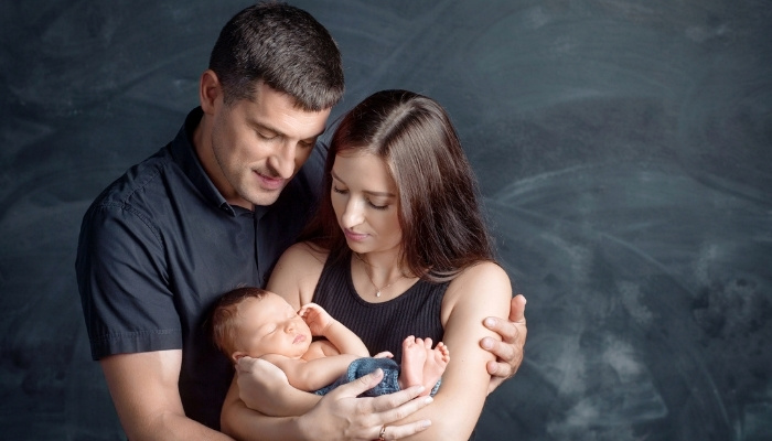 New parents holding and gazing at their newborn.