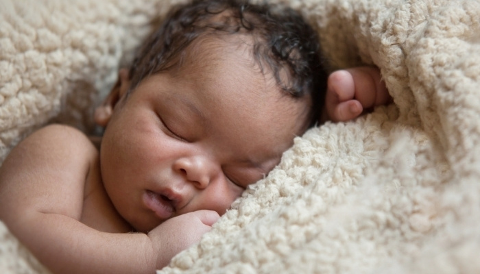 An African-American baby sleeping soundly on a plush blanket.