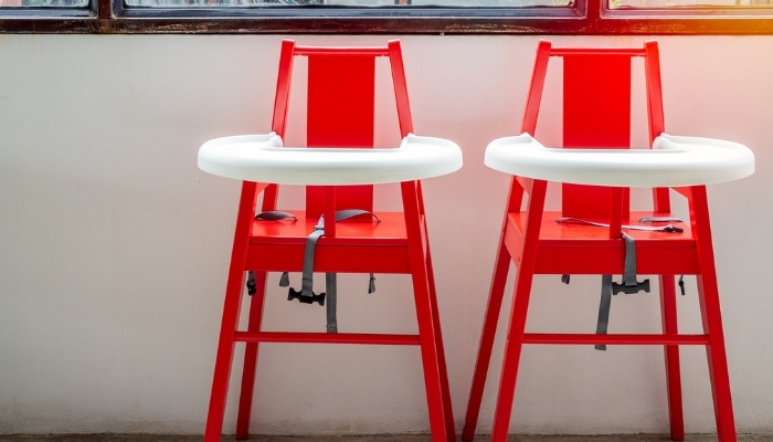 Two red highchairs with white trays.