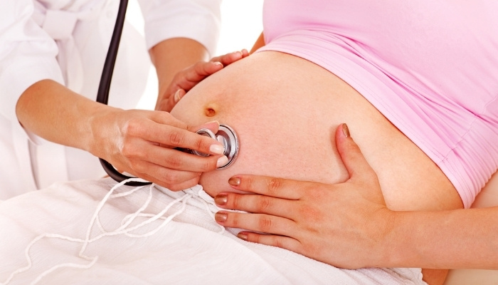 A doctor using a stethoscope to listen for a fetal heartbeat.