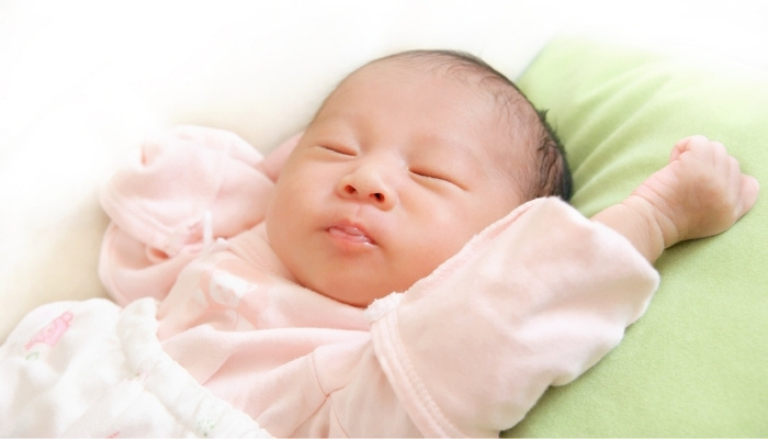 A cute newborn asleep in a baby sleeping bag.