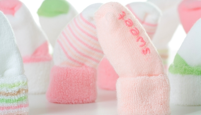Cute green and pink baby socks in a variety of designs standing on their cuffs.