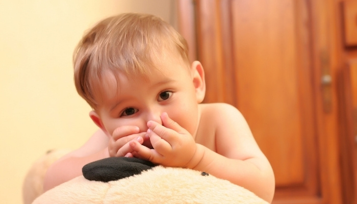 A cute baby boy holding his nose closed.