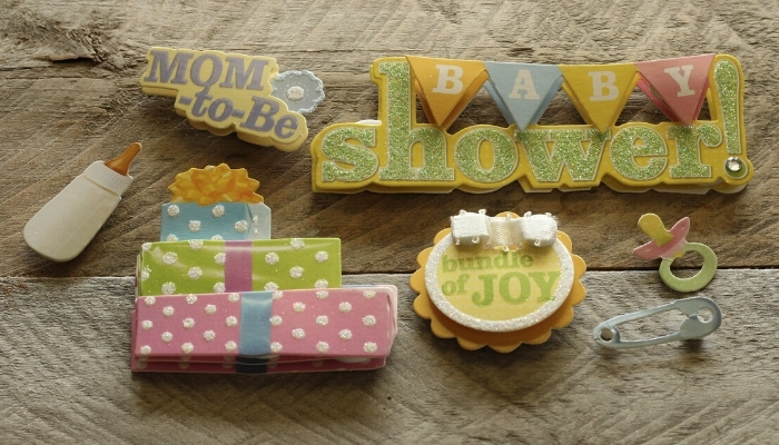 Several cute decorations for a baby shower presented on a wooden table.