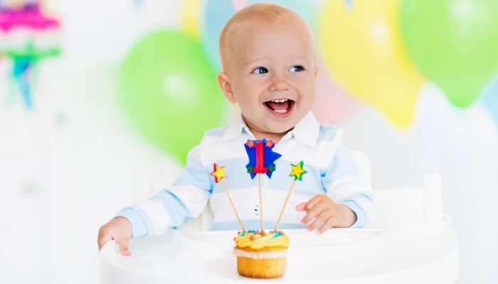 A cute baby boy celebrating his first birthday is very excited about his special cupcake.