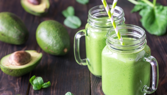 Spinach smoothies with avocado on a kitchen table.