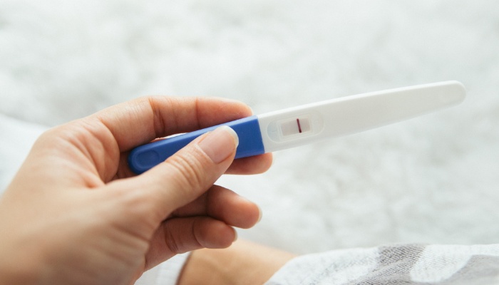 A woman holding a negative pregnancy test in her hand.