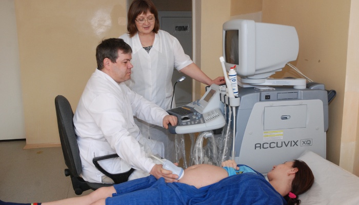 A woman wearing a blue gown receives on ultrasound to check on her pregnancy.