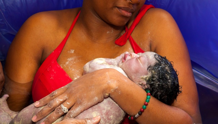 A mother and baby in small pool of water right after a water birth.