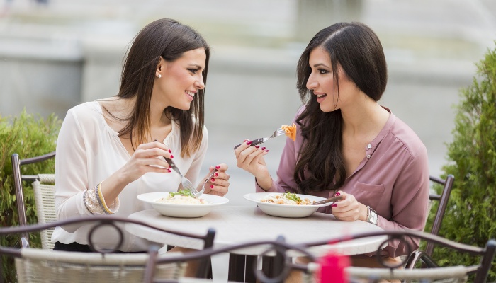 Two women enjoying lunch at a restaurant with outdoor dining.