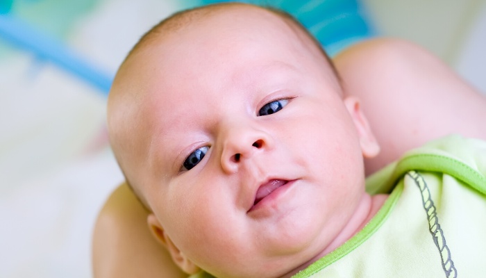 A young baby with his mouth open and tongue showing.